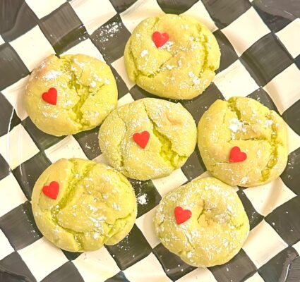 Finished Grinch crinkle cookies with red heart sprinkles on a checkered plate