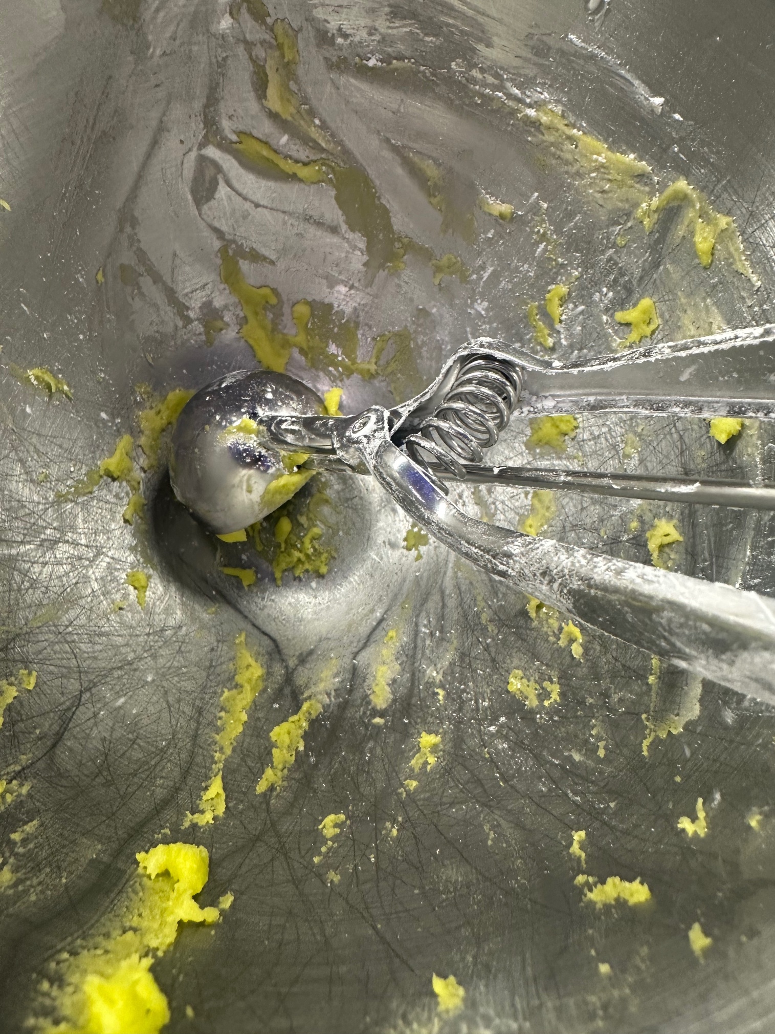Green cake mix cookie dough in a mixing bowl with a cookie scoop