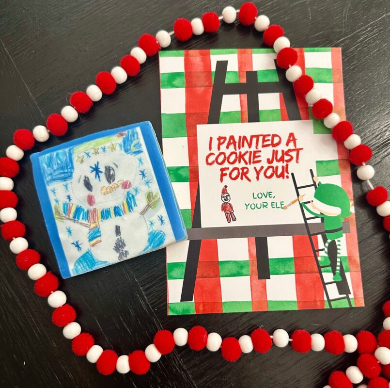 Elf on the Shelf scene with a cookie painted with a child's drawing and a printable “I painted a cookie just for you” backer card