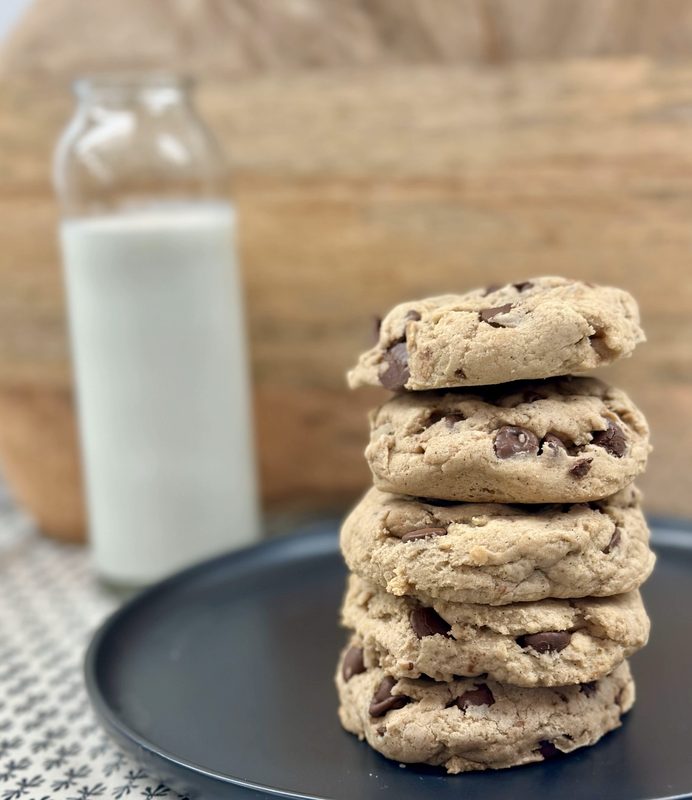 Chocolate chip stack: A stack of thick chocolate chip drop cookies on a plate next to a bottle of milk — an easy first cookie to sell