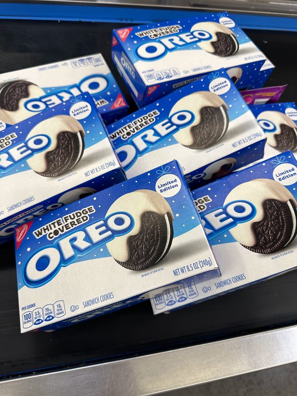 Boxes of limited edition white fudge covered Oreos on a store checkout belt — the store-bought cookies Kathy prints on the Eddie