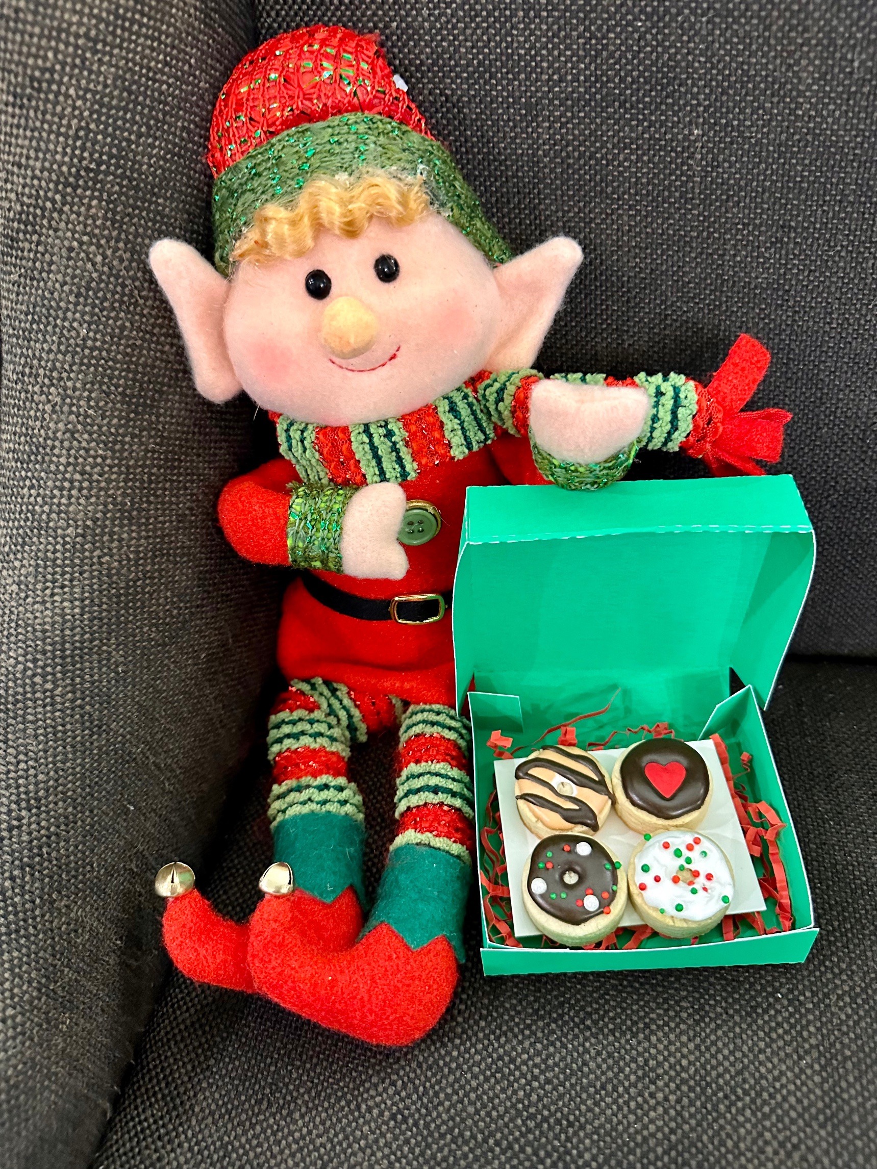Elf holding an open green Dasher's Donuts gift box with mini donut cookies