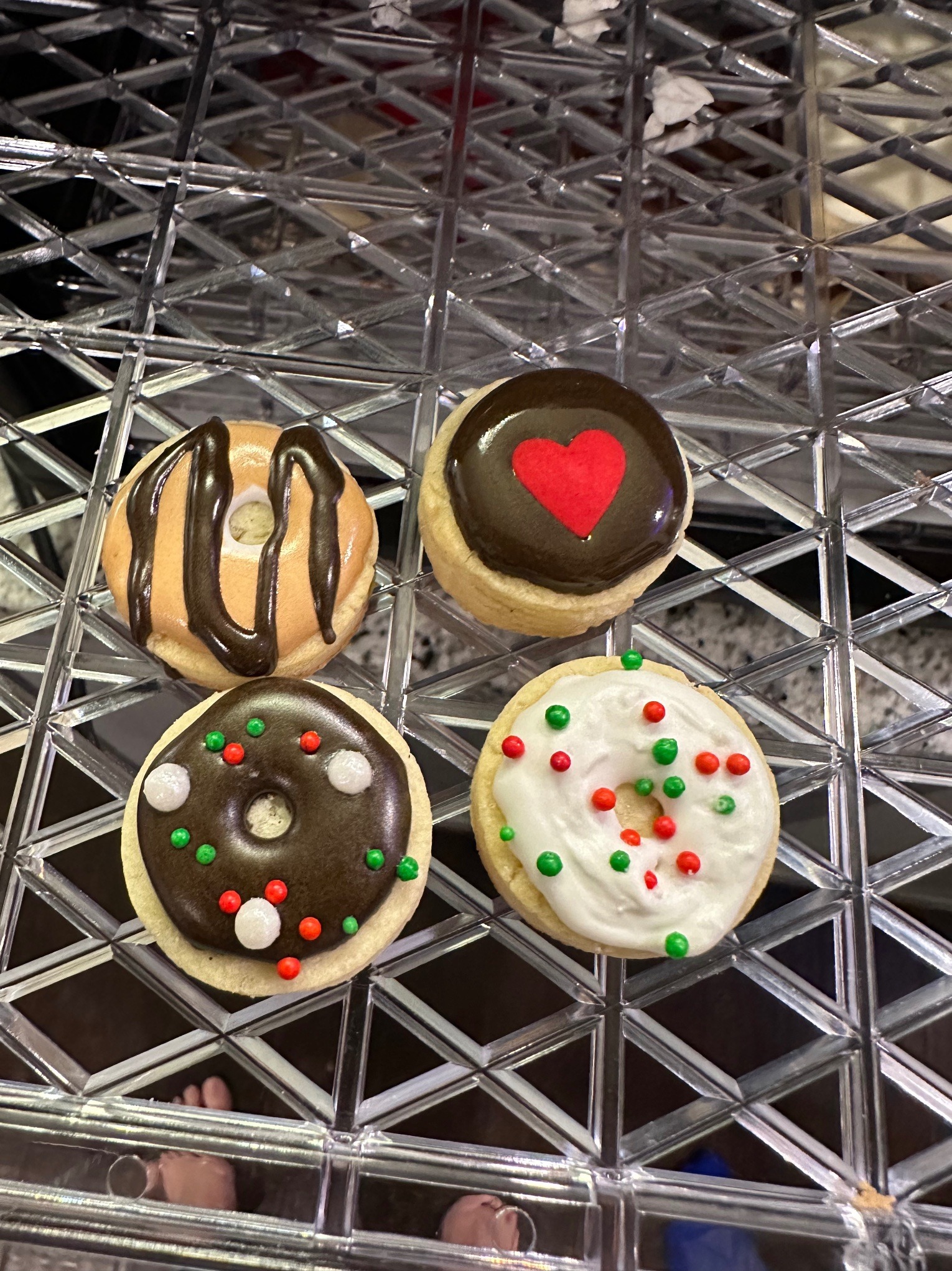 Close-up of four mini donut cookies: chocolate drizzle, chocolate heart, sprinkles