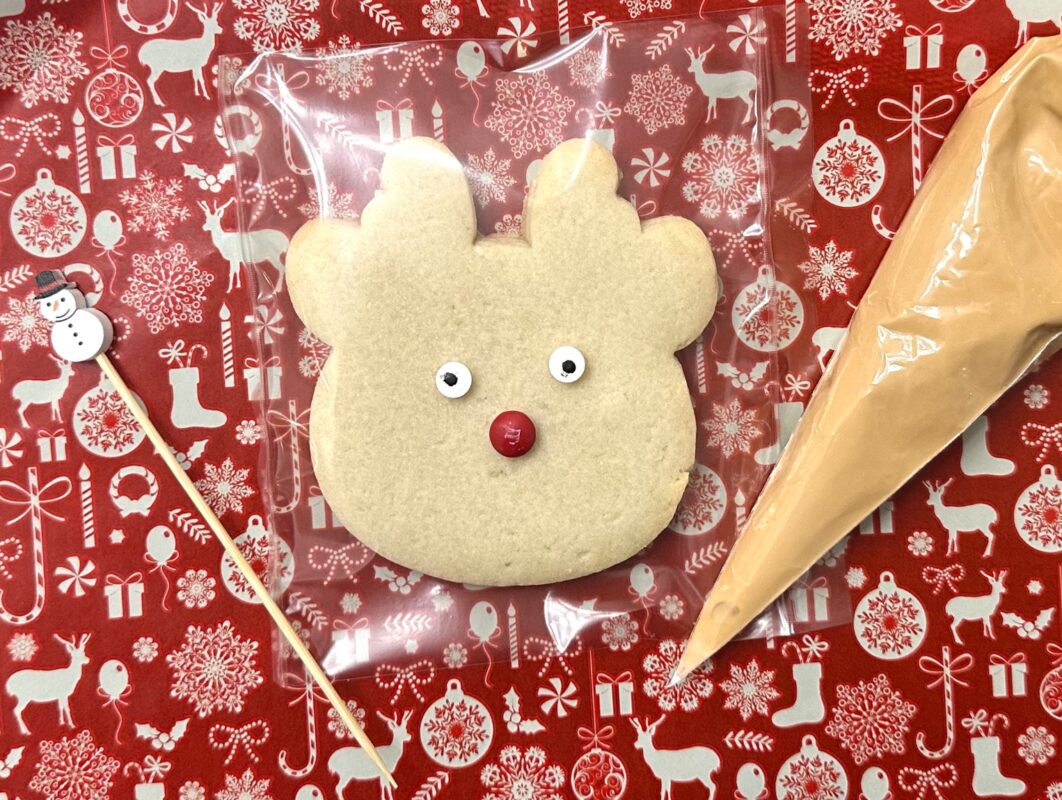 Reindeer DIY cookie kit with undecorated reindeer cookie, candy eyes and an icing bag
