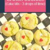 A stack of finished holiday Grinch cake mix crinkle cookies topped with red candy heart sprinkles, presented on a black and white checkered MacKenzie-Childs platter.
